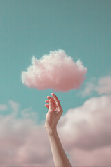Hand gently holding a fluffy cloud against a surreal pastel sky backdrop