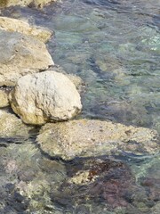 Clear seawater gently flowing over rocks on a sunny day, creating beautiful patterns and reflections
