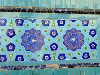 Detailed ceramic tile mosaic featuring intricate geometric and floral designs in blue-turquoise...
