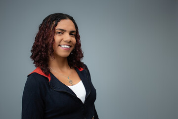 Charming young brown skin woman in casual clothes, smiling at camera. Horizontal studio portrait with copy space on gray background, perfect for positive emotion, motivation and happiness.