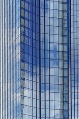 The facade of a modern glass skyscraper reflects the sky