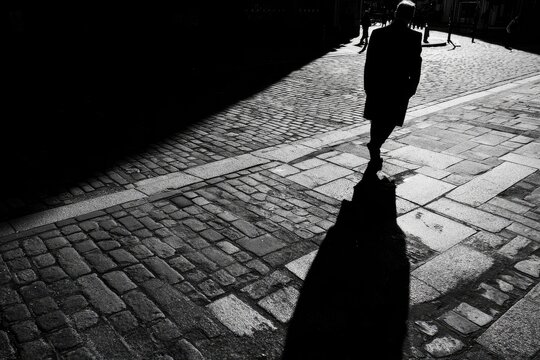 Fototapeta Silhouette of a figure walking in a cobblestone street