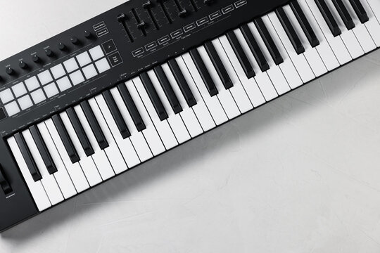 One portable MIDI keyboard on white table, top view. Space for text