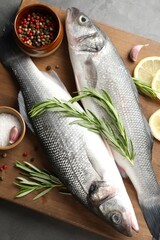 Fresh raw seabass with spices on grey table, top view. Fish and seafood delicacies