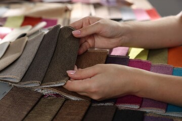 Woman choosing fabric among different samples indoors, closeup