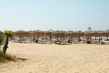 Beautiful straw umbrellas and sunbeds on sandy beach