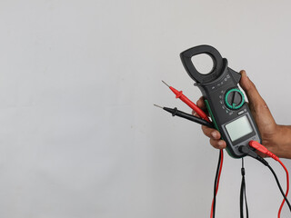 Digital clamp meter held by hand to test current and voltage in electronics isolated on white background 