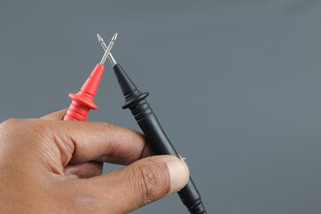 Multimeter probes held by hand to test current and voltage in electronics