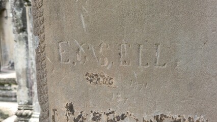 Angkor Wat, Cambodia - 3 July 2025. A stone pillar bears engraved letters and numbers worn by age...