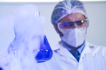 Scientific research concept. A male chemist in a sterile laboratory, wearing full protective gear,...