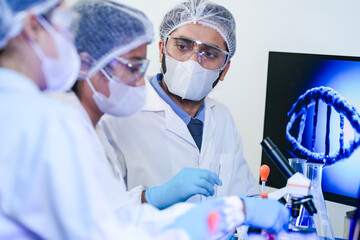 A team of scientists in a modern laboratory meticulously works on an experiment, pipetting a red...