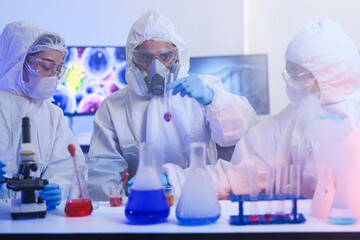 Team of scientists in hazmat suits and respirators conducting a critical experiment in a...