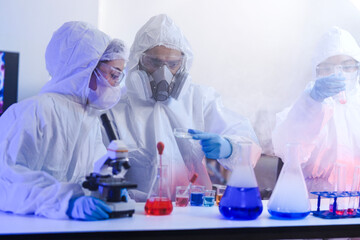 Team of scientists in hazmat suits and respirators conducting a critical experiment in a...
