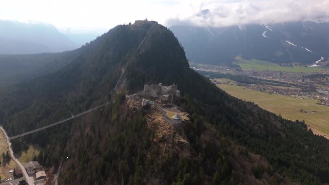 Aerial view of Ehrenberg Castle complex near Reutte, Tyrol, Austria. The medieval Ehrenberg ruins, Schlosskopf Fortress, and the iconic highline179 suspension bridge set in the stunning Lechtal Alps. 
