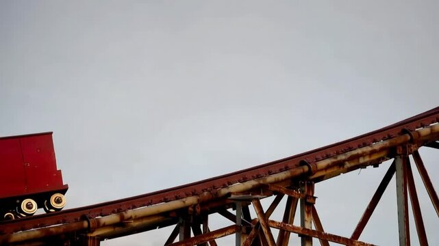 A roller coaster cart climbing to the peak of the track at an empty amusement park, with the click-clack of the chains echoing in the otherwise still air.
