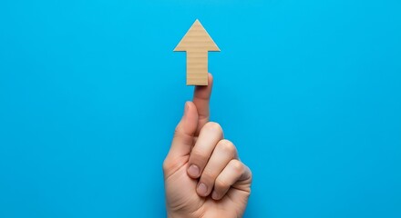 Cardboard arrow pointing upwards on finger image