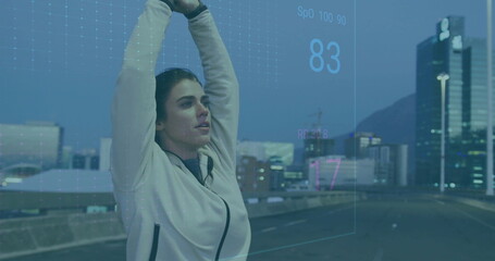 Stretching athlete wearing jacket raising arms overhead on bridge at dusk with biometric metrics