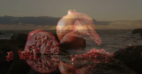 Blending whole and sliced pomegranate with rocky beach shoreline at sunset, revealing glossy arils