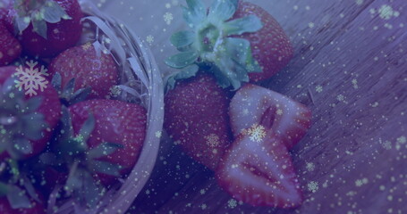 Displaying glass bowl brimming with whole, sliced strawberries on kitchen table, with snowflakes