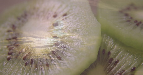 Displaying three green kiwi fruit slices on brown cutting board, highlighting radial seed pattern