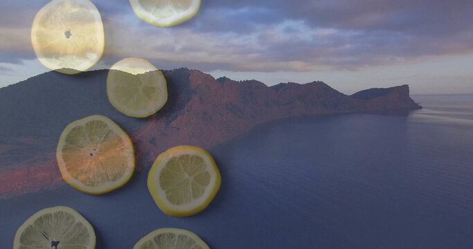 Fototapeta Featuring rugged mountain peninsula jutting into quiet sea at dusk, with translucent lemon slices