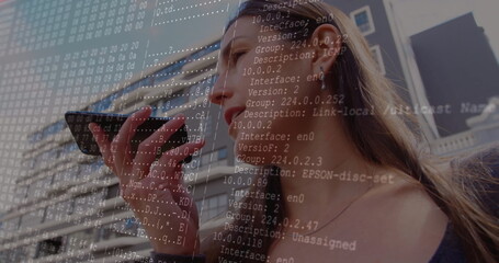 Adult man speaking into smartphone before office building facade, wired earphones, network overlay