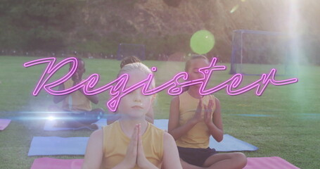 Sitting children pressing hands together on colorful yoga mats at park field, with soccer goalposts
