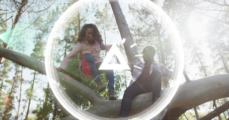 Climbing friends balancing on large tree trunk in sunlit pine forest, with digital triangle graphic