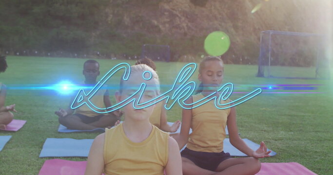Sitting children wearing yellow sportswear on grassy sports field, with yoga mats and soccer nets