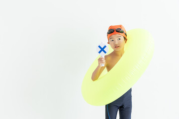 バツのプレートを持った水着を着た男の子	