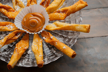 Traditional Colombian dessert platter featuring fried pastries (deditos) with powdered sugar,...