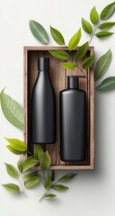 Two matte-black bottles, one pump, one cap, nestled in a rustic wooden crate surrounded by lush green leaves against a bright white backdrop