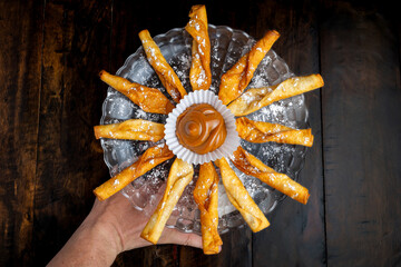 Traditional Colombian dessert platter featuring fried pastries (deditos) with powdered sugar,...
