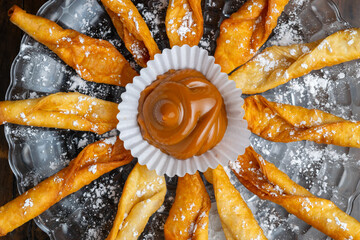 Traditional Colombian dessert platter featuring fried pastries (deditos) with powdered sugar,...