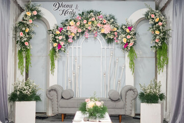 Romantic Wedding Stage with Tufted White Sofa, Floral Arch Featuring “Diana & Holy”, and...