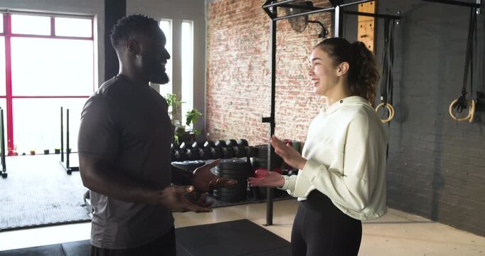 After greeting trainer and female client discussing workout plan and checking form by rack