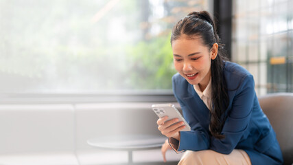 Fototapeta premium Businesswoman using smartphone in modern office: enjoying mobile technology