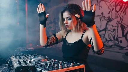 In a small club adorned with graffiti, a young female DJ in fishnet gloves and a mesh top ignites the crowd by throwing her hands in the air