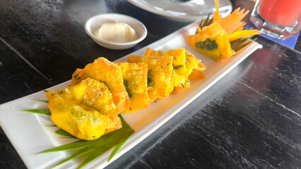 Golden fried wontons filled with creamy spinach and melted cheese, gourmet Asian fusion snack close-up,Crispy fried wontons stuffed with spinach and cheese, golden brown snack