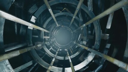 A wind turbine shaft from a unique vertical angle, highlighting the structural components within an industrial environment. The perspective emphasizes depth and design