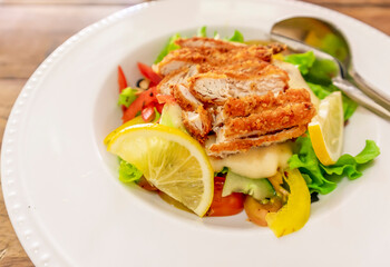 Frresh healthy vegetable salad of Lettuce, tomato, cucumber, olives, red pepper and lemon slice topped with chicken cutlets, banner, top view