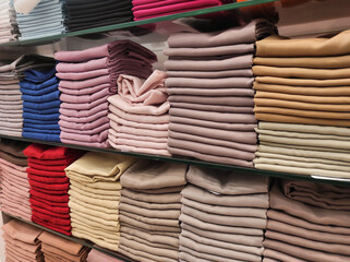Hijab fabrics are neatly arranged on store shelves in a variety of colors. Satin, cotton, and silk fabrics are displayed on shelves, arranged by color and gradation. Muslim women's fashion. Copy space
