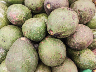 A pile of avocados that look stale in the supermarket. Avocados with skins that have begun to turn black indicate they are starting to rot. Fruit and vegetables on display in the supermarket. Ad space
