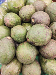A pile of avocados that look stale in the supermarket. Avocados with skins that have begun to turn black indicate they are starting to rot. Fruit and vegetables on display in the supermarket. Ad space