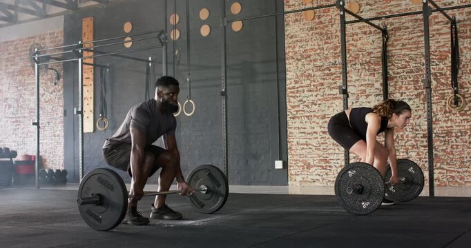Diverse workout partners starting hip-hinge in gym, deadlifting loaded barbells for strength