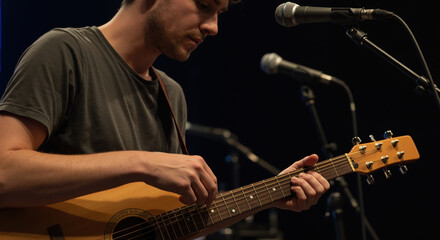 Young man playing musical instrument on stage during performance  