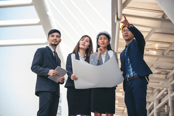 Group of construction engineer look at blueprint architecture building contractor design in modern city. Partner team engineer holding project planing project teamwork. Engineering construction site