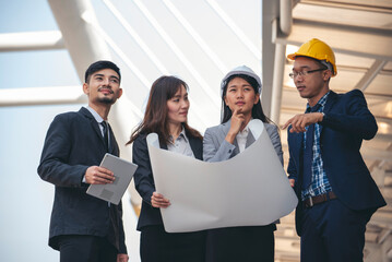 Group of construction engineer look at blueprint architecture building contractor design in modern city. Partner team engineer holding project planing project teamwork. Engineering construction site