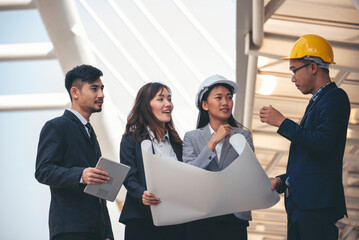 Group of construction engineer look at blueprint architecture building contractor design in modern city. Partner team engineer holding project planing project teamwork. Engineering construction site