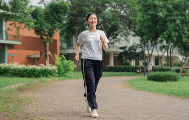 Woman running outdoors on brick path in park exercise healthy lifestyle smile workout trees